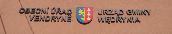 Dwa zdjęcia obok siebie. Na pierwszym zdjęciu znajduje się fragment elewacji domu, na którym są przymocowane poszczególne litery nazwy urzędu gminy. Wlewo jest czeska nazwa „Obecní úřad Vendryně”, wprawo znajduje się „Urząd gminy Wendrynia”. Pomiędzy widnieje znak gminy. Czeski i polski napis są formalnie identyczne. Także drugie zdjęcie przedstawia fragment elewacji domu i zainstalowaną na nim białą, metalową tablicę w kształcie prostokątu. Niebieską czcionką w środku tablicy zapisano „Školní družina / Świetlica szkolna”. U góry są dwa mniejsze napisy – „Základní škola s polským jazykem vyučovacím / Szkoła podstawowa z polskim językiem nauczania”. Pod spodem widnieje adres placówki – „Český Těšín, Havlíčkova 13, okres Karviná”. Graficznie są dwujęzyczne napisy tożsame.