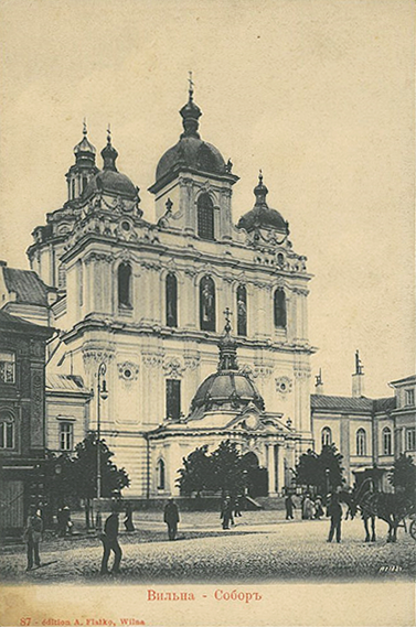 A historic baroque-style cathedral with multiple domes stands in a town square where people and a horse-drawn carriage are present.
Description generated by AI